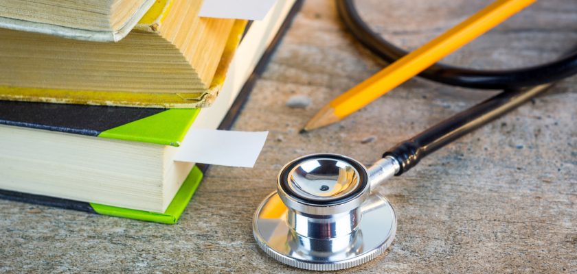 Medical student textbooks with pencil and white bookmarks and stethoscope